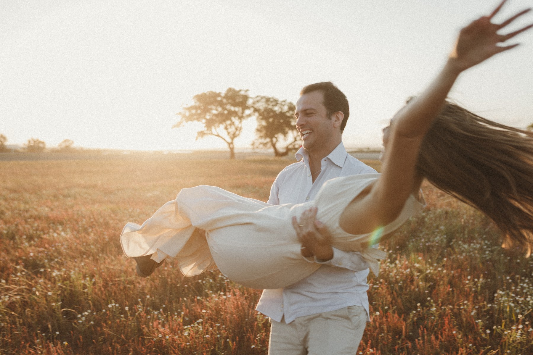 Casal a rodopiar num campo ao pôr do sol