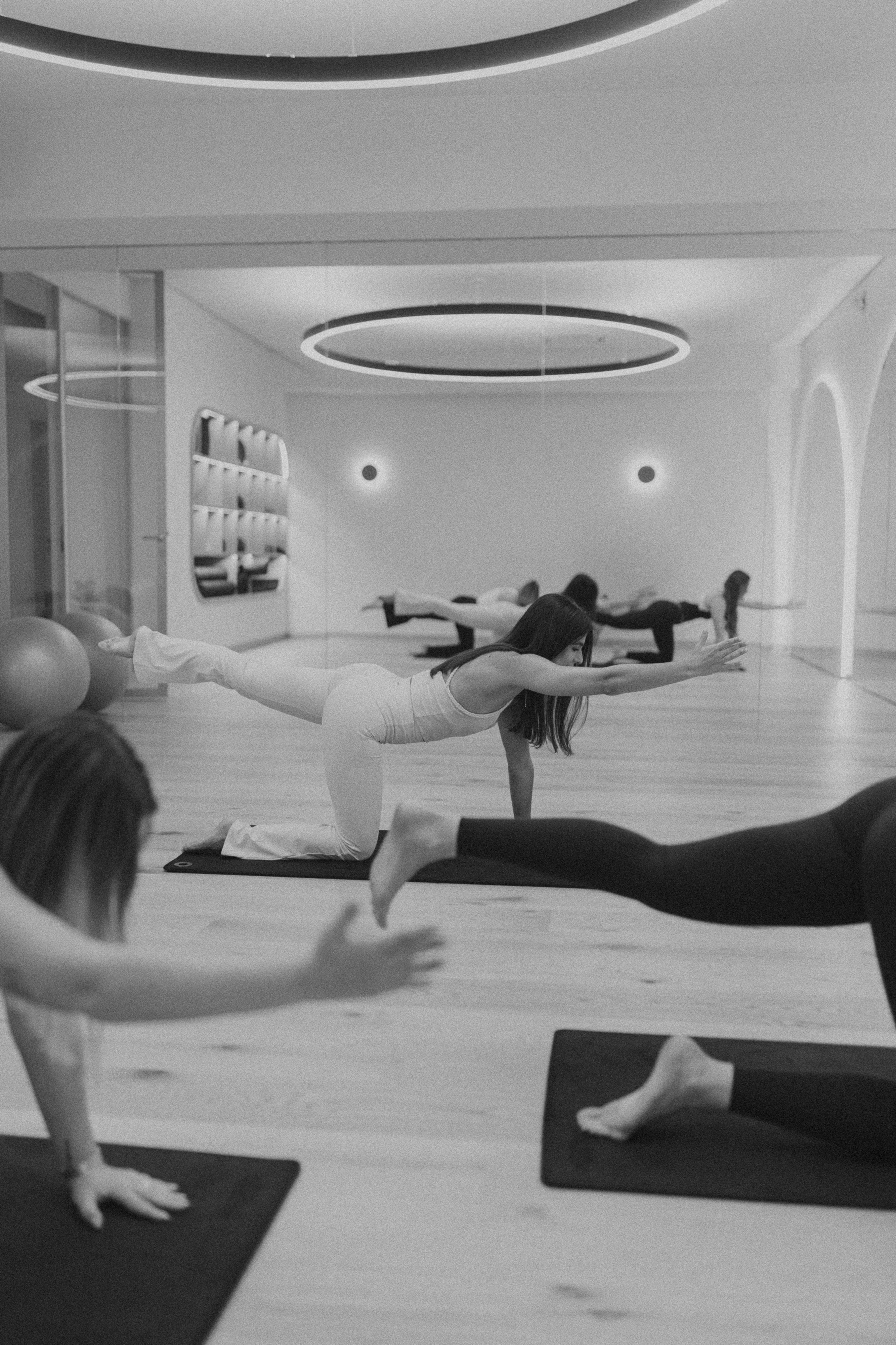 Aula de pilates num estúdio com espelhos e luz suave, a preto e branco